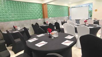 A conference room with round tables, black chairs, and a green textured wall.