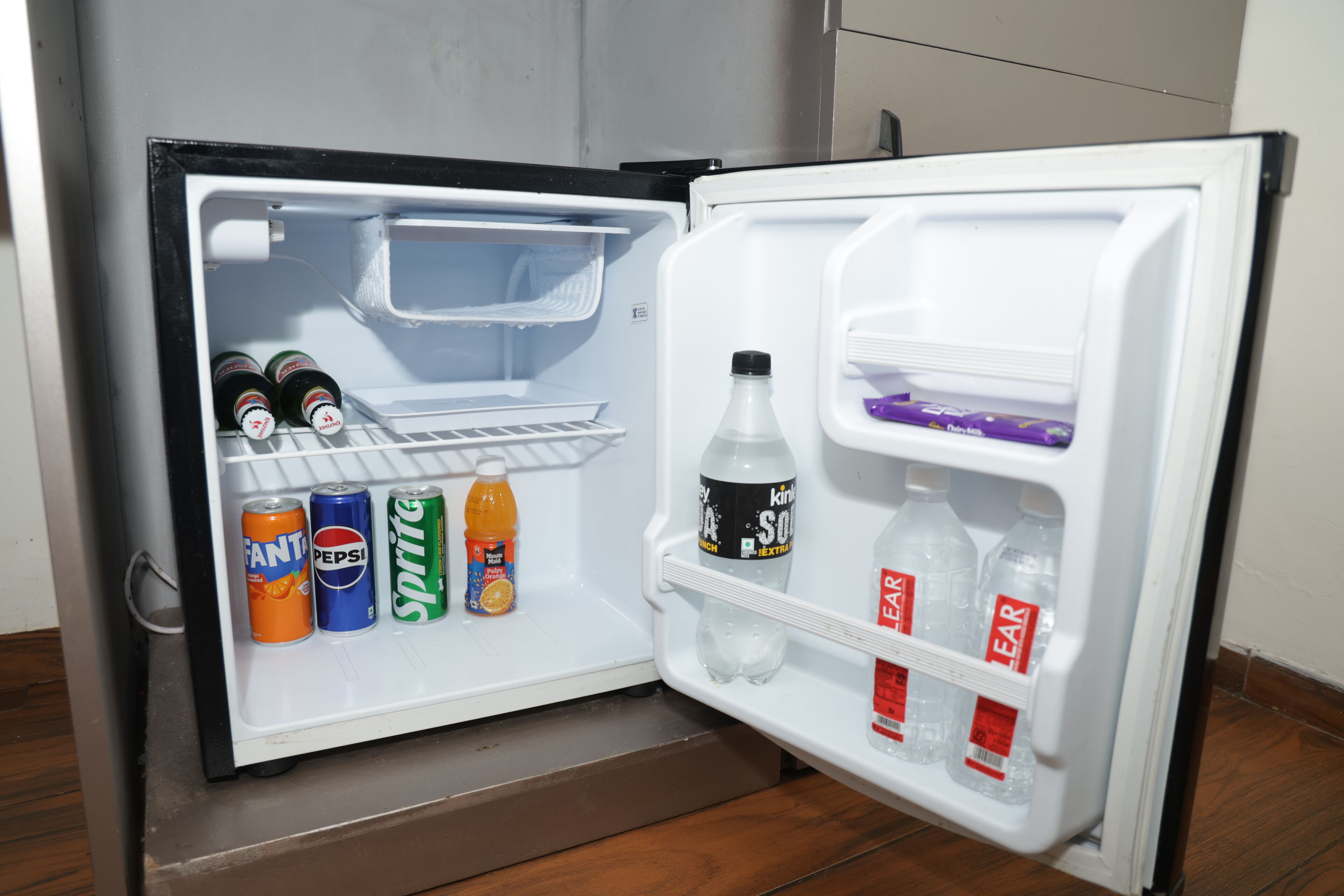 Un mini-réfrigérateur contenant des boissons, notamment du Fanta, du Pepsi, du Sprite et de l’eau.