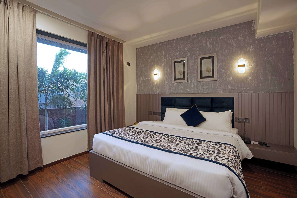 A neatly made bed with a patterned bedspread, a headboard, and two wall-mounted lights.