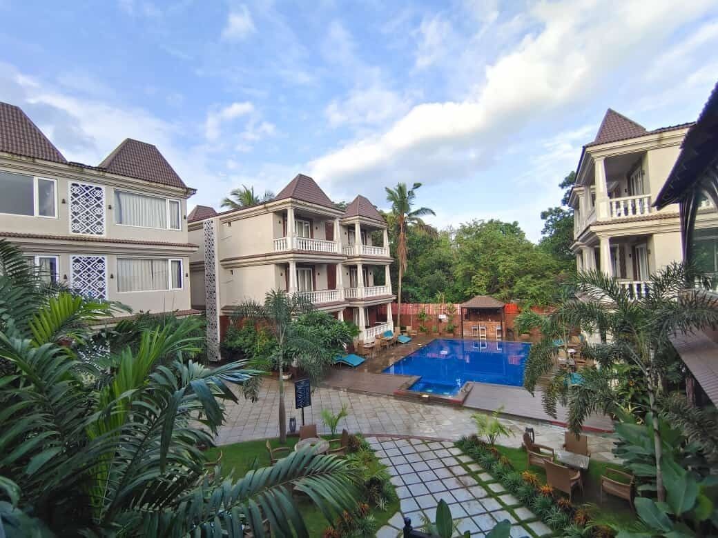 Ein Resort mit mehrstöckigen Gebäuden, einem Schwimmbad und üppiger Bepflanzung.
