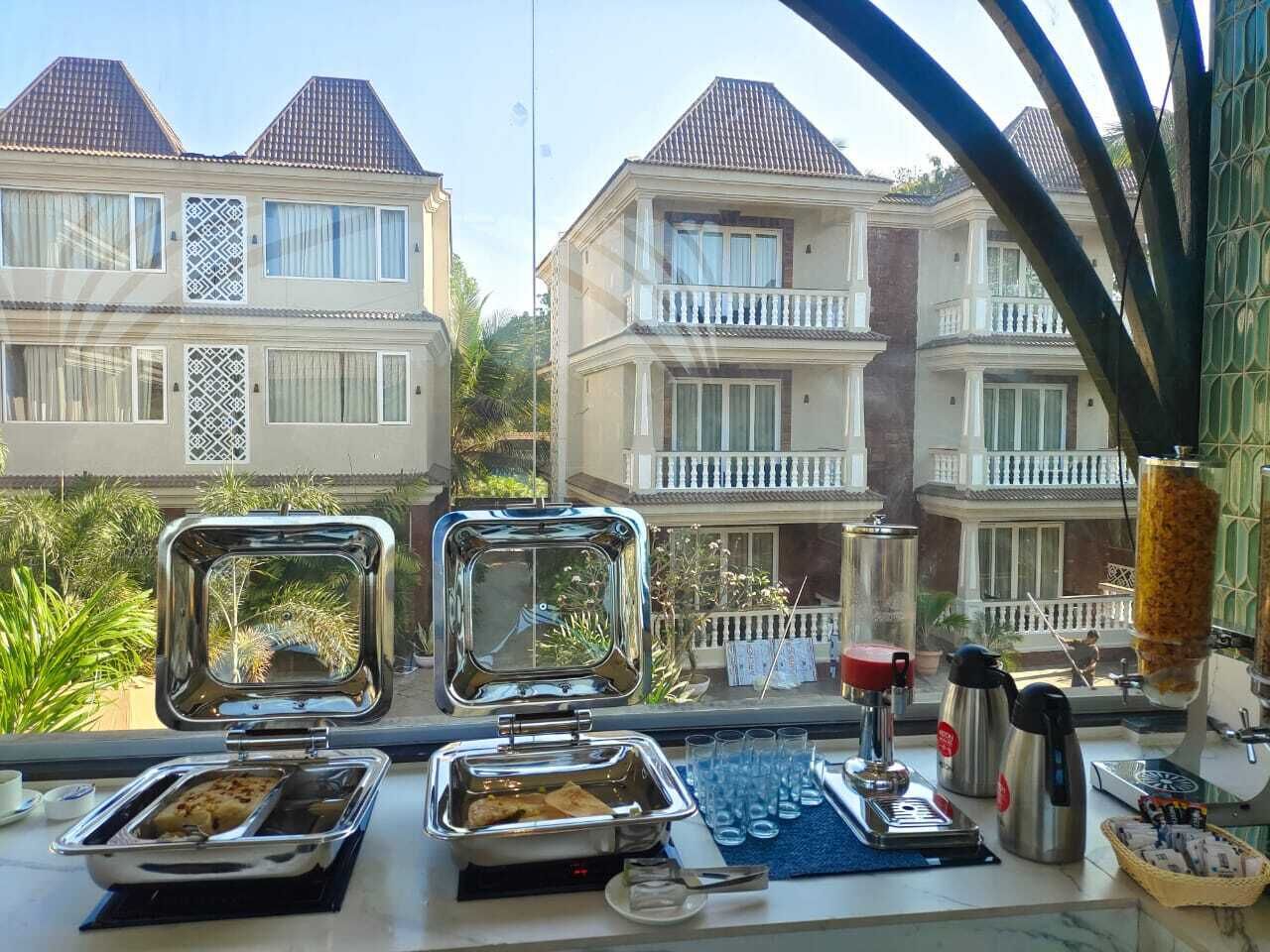 A buffet setup with trays of food, a coffee maker, and a beverage dispenser.