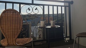 A balcony with wicker chairs, a table with cups, and a decorative metal railing. - Luxury Apartment (Hengchun)