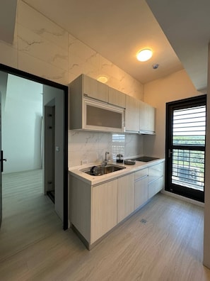 A modern kitchen with a built-in microwave, a sink, and light wood cabinetry.