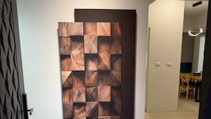 A hallway with a modern wall art piece and a dining area in the background. - Luxury Apartment (Hengchun)