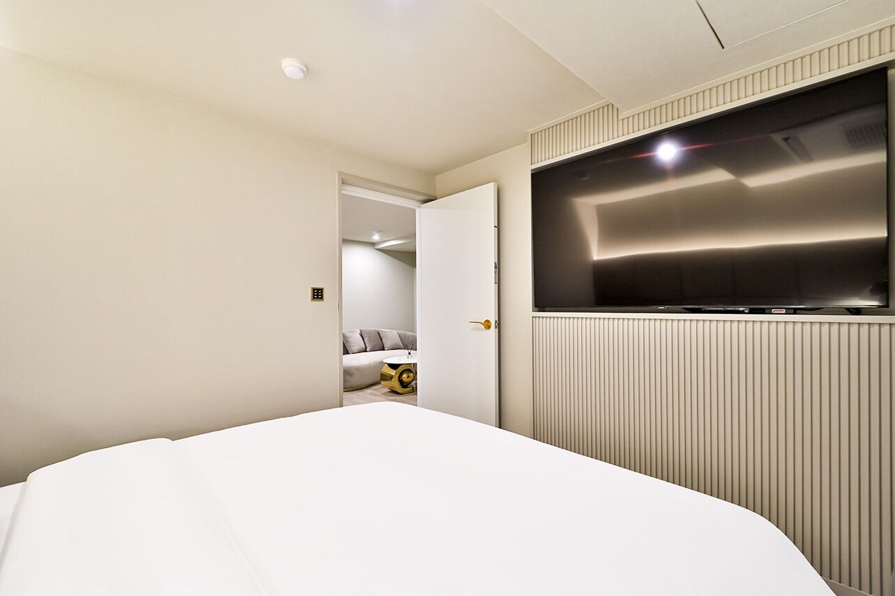 Ein modernes Hotelzimmer mit einem großen Bett, einem an der Wand befestigten Fernseher und einer Tür zu einem Badezimmer.