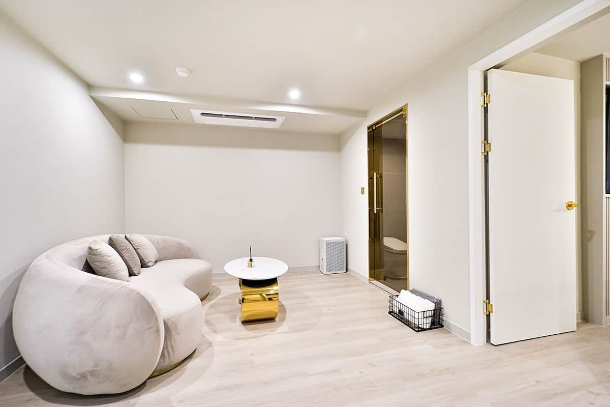 Una habitación moderna y minimalista con un sofá curvo, una pequeña mesa redonda y un espejo grande.