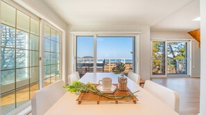 A dining area with a table set for two, large windows, and a view of the sea. - Boryeong Thirasel Pension (Boryeong)