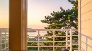 A view from a window with a white railing, overlooking a body of water and a distant shoreline with trees. - Boryeong Thirasel Pension (Boryeong)