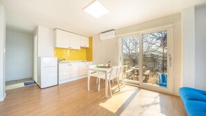 A modern kitchen with white cabinets, a yellow backsplash, and a dining area with white chairs. - Boryeong Thirasel Pension (Boryeong)