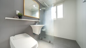 A modern bathroom with a white sink, a toilet, a mirror, and a shower with a frosted glass door. - Boryeong Thirasel Pension (Boryeong)