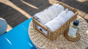 A wicker basket with folded towels and a bottle of Moment Lavender Sandalwood body spray on a woven mat. - Boryeong Thirasel Pension (Boryeong)