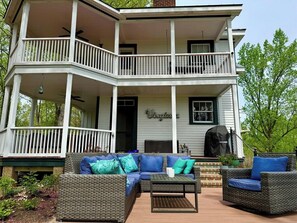 A two-story house with a porch, outdoor furniture, and a grill.