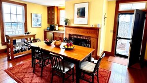 Una sala da pranzo con un tavolo di legno, sedie, una ciotola di frutta e un camino.