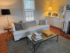 Een woonkamer met een bank, een salontafel, een lamp en een boekenkast.