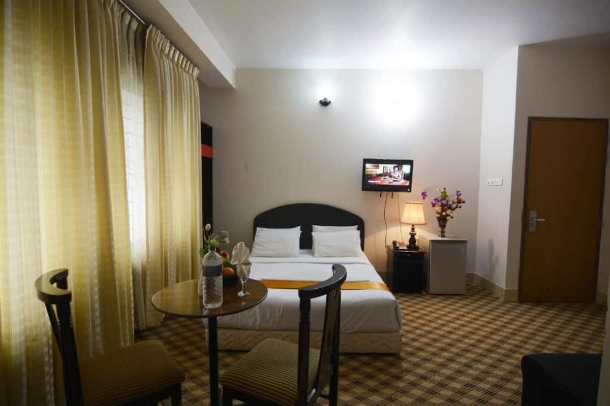 Une chambre d’hôtel avec un lit, une télévision, une petite table avec une lampe et une chaise.