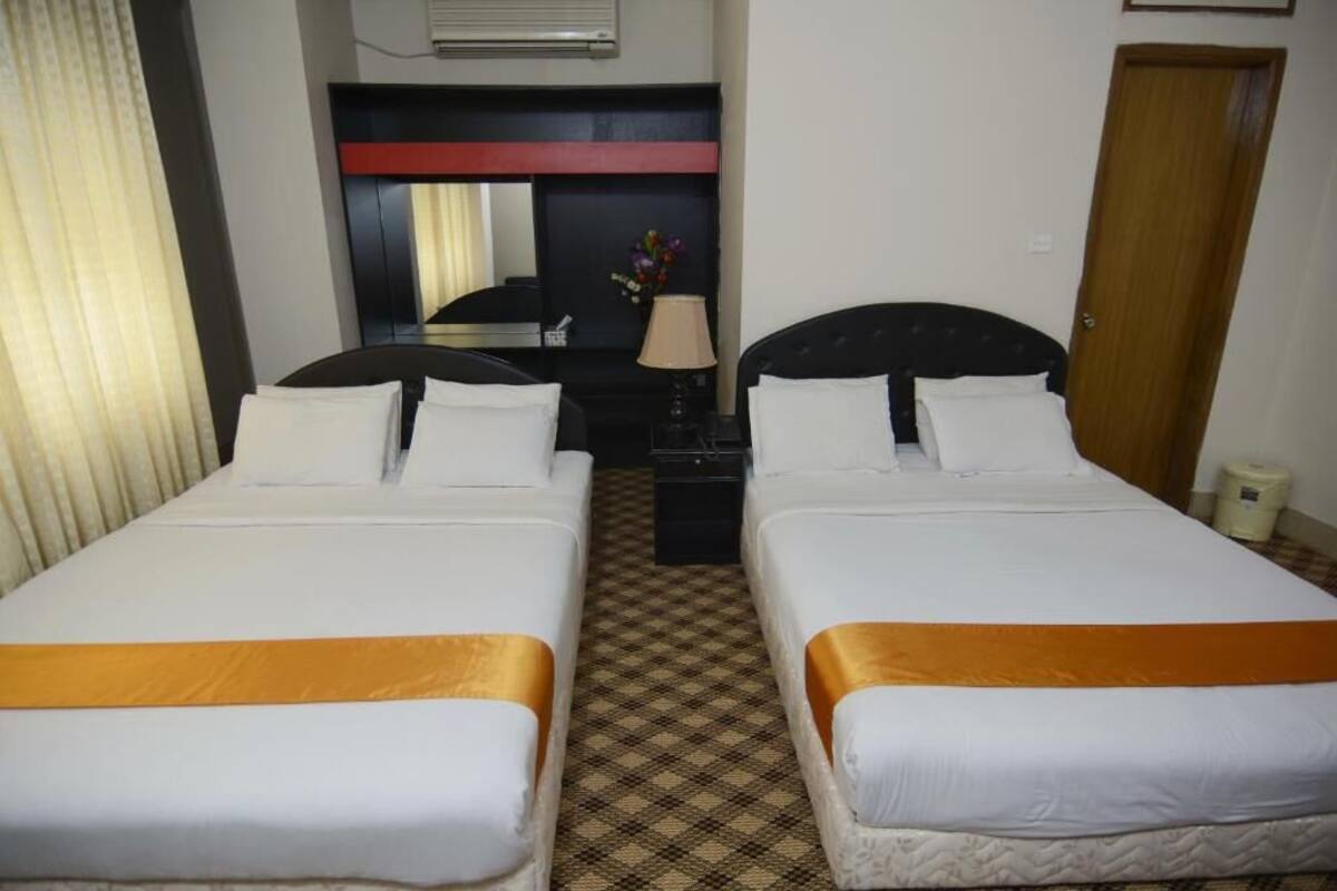 Une chambre d’hôtel avec deux lits, un miroir, un bureau et une lampe.