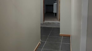Un couloir étroit, avec un sol carrelé et des murs blancs.