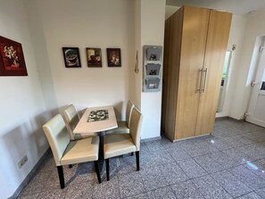 A dining area with a table and four chairs, a wooden wardrobe, and three framed pictures on the wall. - Rudolph by Interhome (Zinnowitz)