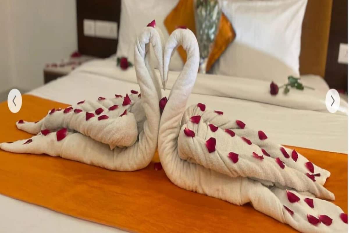 A bed with a white and orange bedspread, a wooden headboard, and white pillows.