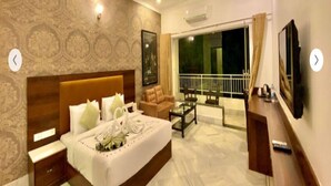 A hotel room with a bed, a nightstand, a desk, a chair, a balcony with a view, and a ceiling fan. - Mewar Palace Resort & Spa (Udaipur)