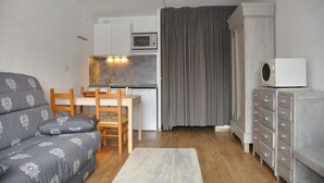 Un espace de vie compact comprenant un canapé, une table à manger avec des chaises, un coin cuisine, un four à micro-ondes et un placard.
