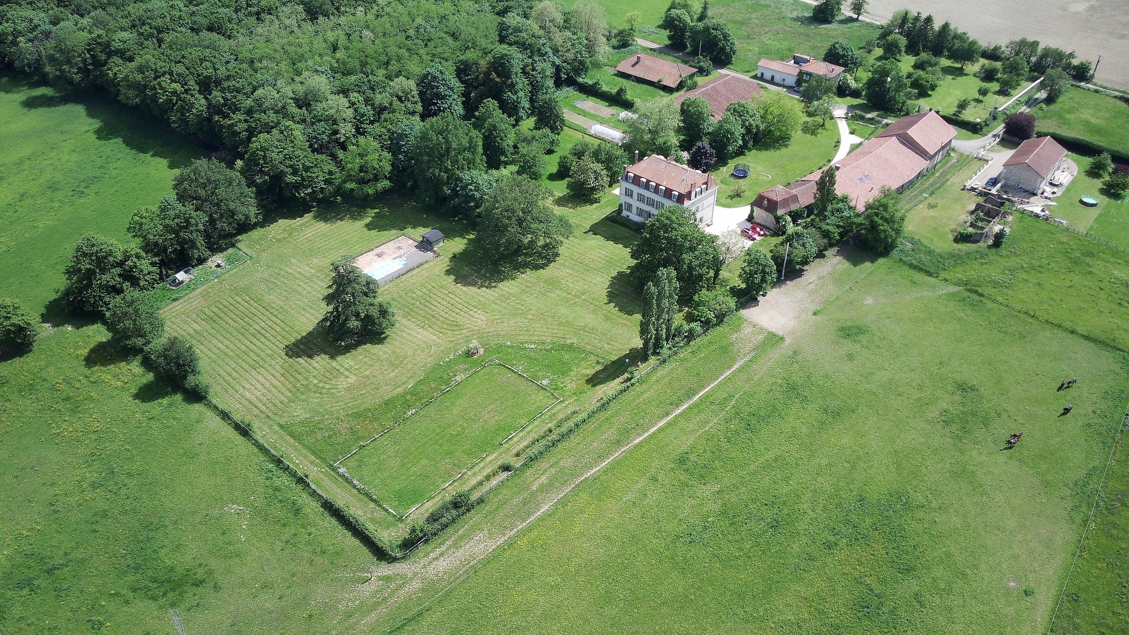 Luchtbeeld van een woongebied met huizen, groene velden en een groot open veld.