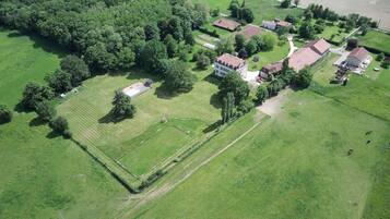 Luchtbeeld van een woongebied met huizen, groene velden en een groot open veld.