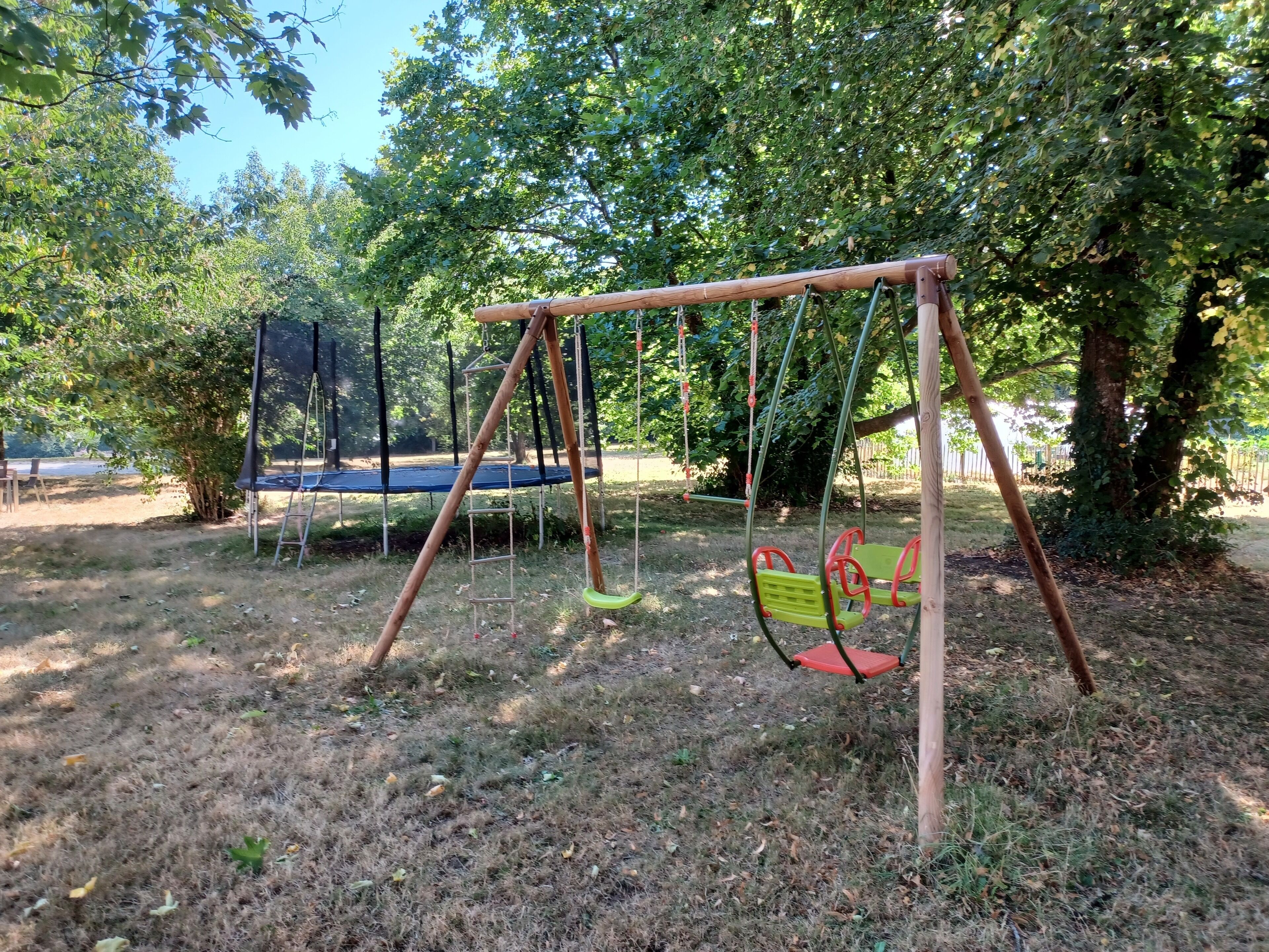 A playground with a swing set and a trampoline.