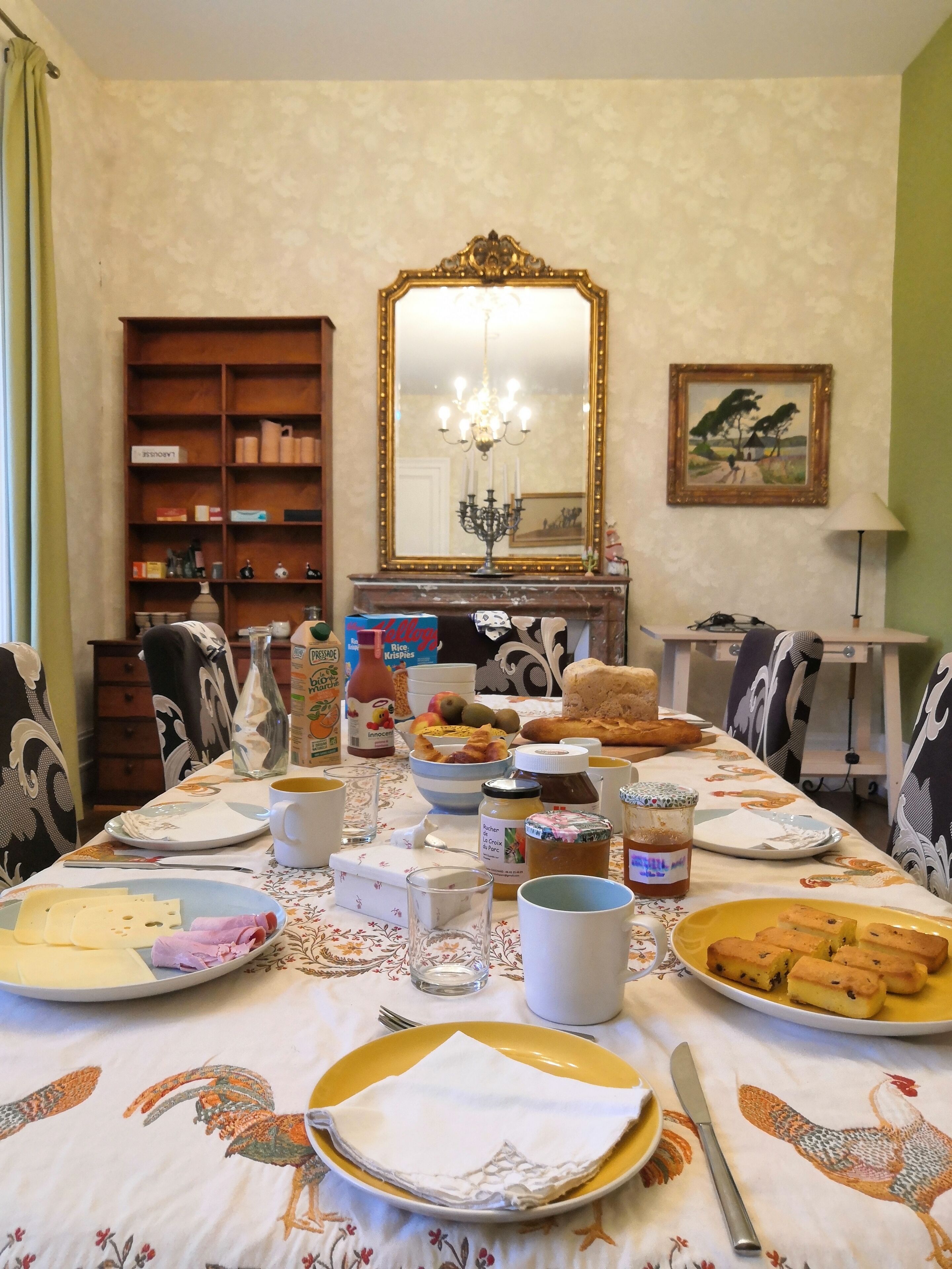 Uma mesa de jantar posta com diversos pratos, um espelho e um lustre.
