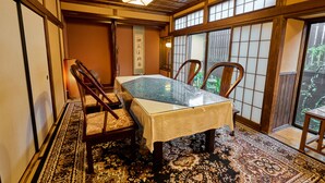A traditional Japanese room with tatami flooring, a low table with a glass top, and sliding doors with a view of greenery outside. - Kigannoyado Aoshima Jizoan (Miyazaki)