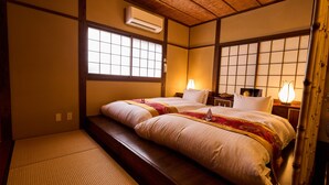 A traditional Japanese-style room with tatami flooring, two beds with bedding, a shoji screen, and a wooden ceiling. - Kigannoyado Aoshima Jizoan (Miyazaki)