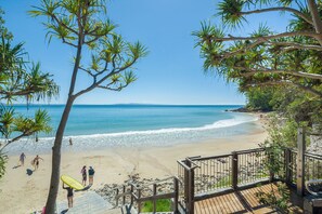 A beach with a wooden deck and a railing, overlooking the ocean.