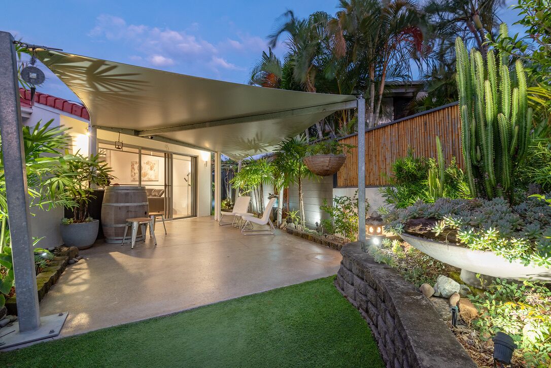 An outdoor patio area with a covered seating area, potted plants, and a stone wall.