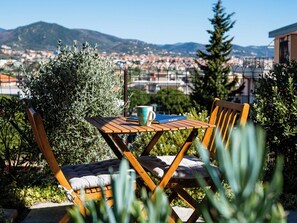 Un espace extérieur aménagé avec une table et des chaises, un livre et une tasse.