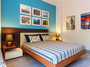 Une chambre à coucher avec un lit, deux tables de chevet, une tête de lit et un mur orné de tableaux.