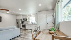 A modern kitchen with white cabinets, a dining table with chairs, and a sofa. - Serene Space, Explore Nearby Attractions (Fresno)