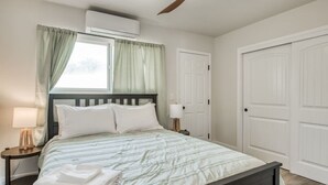 A bedroom with a bed, a nightstand, a lamp, an air conditioning unit, a ceiling fan, and two white doors. - Serene Space, Explore Nearby Attractions (Fresno)