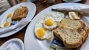 Ein Frühstückstisch mit Toast, Spiegeleiern und Saft.