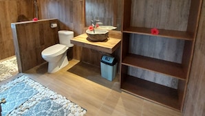 Ein Badezimmer mit einem Holzkosmetikschrank, einer Toilette, einer Dusche und einer kleinen Mülleimer.