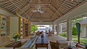 A spacious indoor area with a high ceiling, a dining area, and a view of the sea. - Siri Mendira Beach Villas (Manggis)