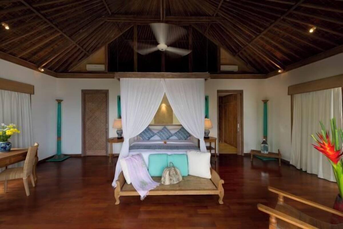 Quarto espaçoso com uma cama grande, ventoinha no teto e piso de madeira.