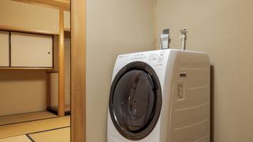 A compact room with a washing machine, a small cabinet, and a tatami mat floor.