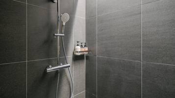 A modern shower with a handheld showerhead and a wall-mounted rain showerhead.