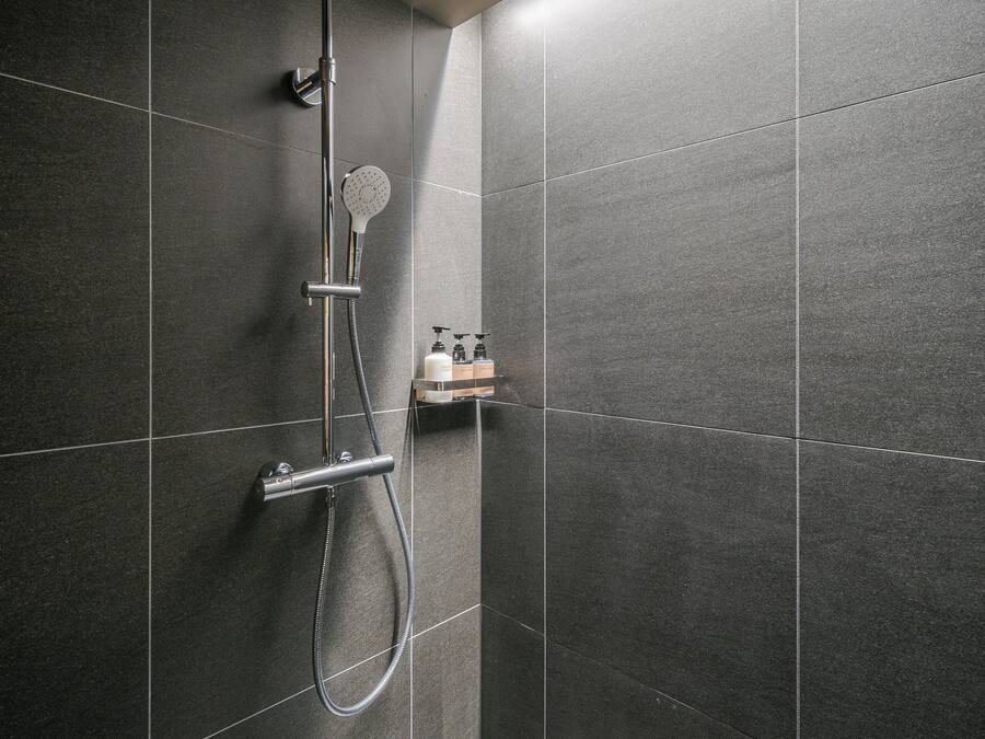 A modern shower with a handheld showerhead and a wall-mounted rain showerhead.