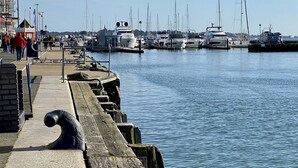 Een jachthaven met boten aan een waterkantpromenade.