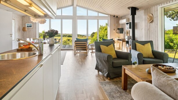 Uma cozinha moderna com uma ilha grande, uma sala de jantar com vista e um espaço de estar aconchegante com lareira.