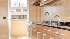 Una cocina moderna con armarios de madera, electrodomésticos de acero inoxidable y un amplio ventanal con vistas a la ciudad.
