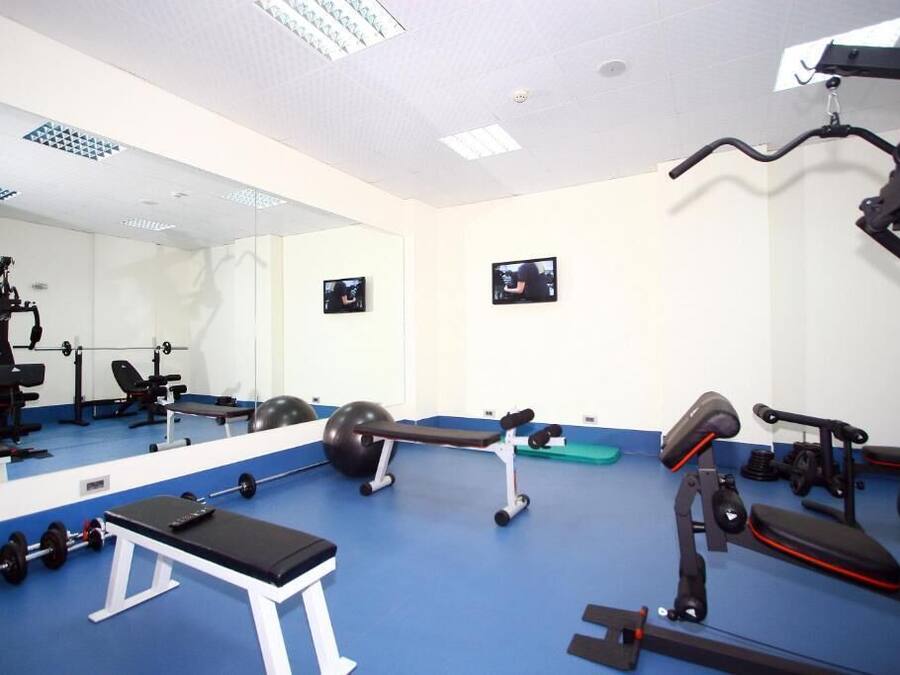 Un gimnasio con equipo de ejercicio, una banca y un espejo grande.