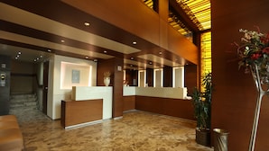 Zona de recepción con mostrador, escalera y planta en maceta.