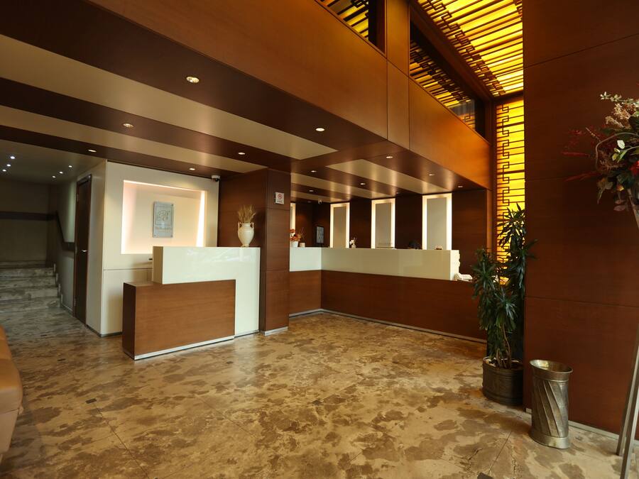 A reception area with a reception desk, a staircase, and a potted plant.